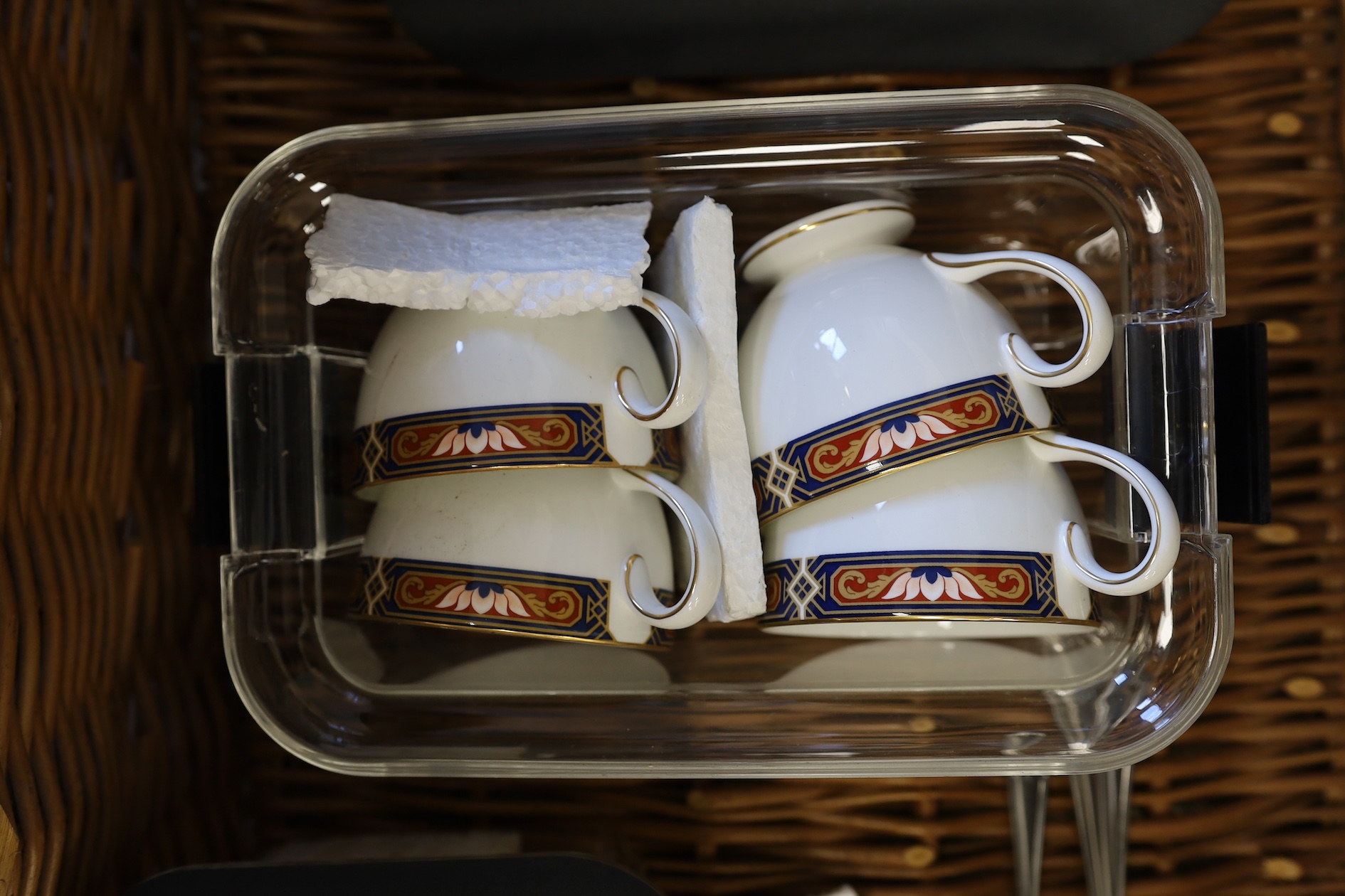 A Harrods wicker picnic hamper for four persons, with Wedgwood plates, cups and saucers, plated cutlery and wine glasses. Condition - good